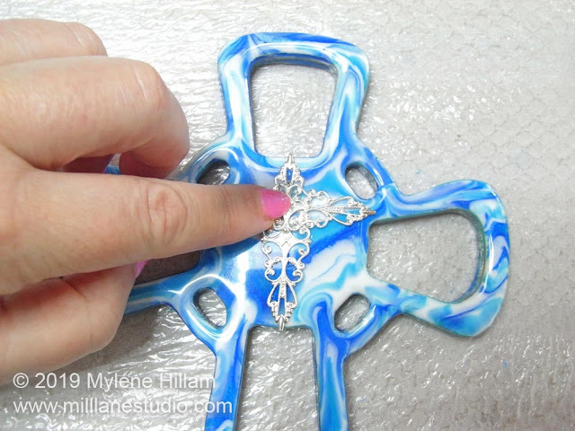 Positioning a second filigree at right angles to the first one to create a cross.