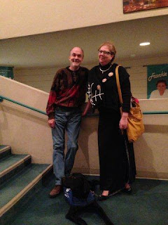 Fred, Cheryl and a calm Coach, who is lying down on the carpet, relaxed and at  peace now that he is outside the actual seating area and on the steps leading inside. 