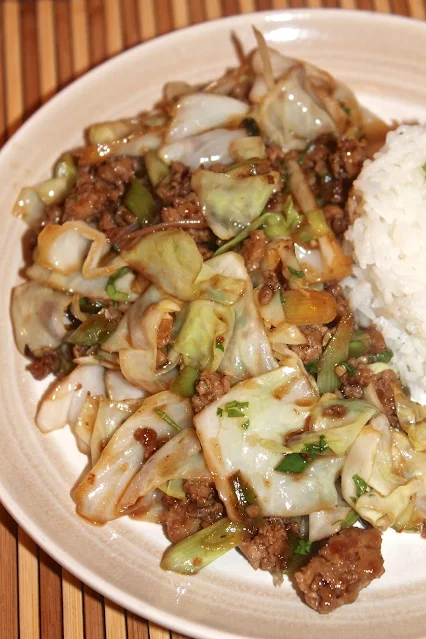 Plate of pork and cabbage stir fry with rice.