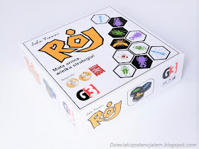 Pudełko od gry Rój kwadratowe w białym kolorze, na wierzchniej części narysowane są płytki do gry i symbole nagród i wyróżnień dla gry między innymi od od Mensa, 