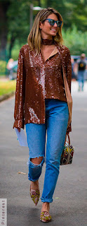 Mulher andando usando camisa marrom, calça jeans e mule com flor