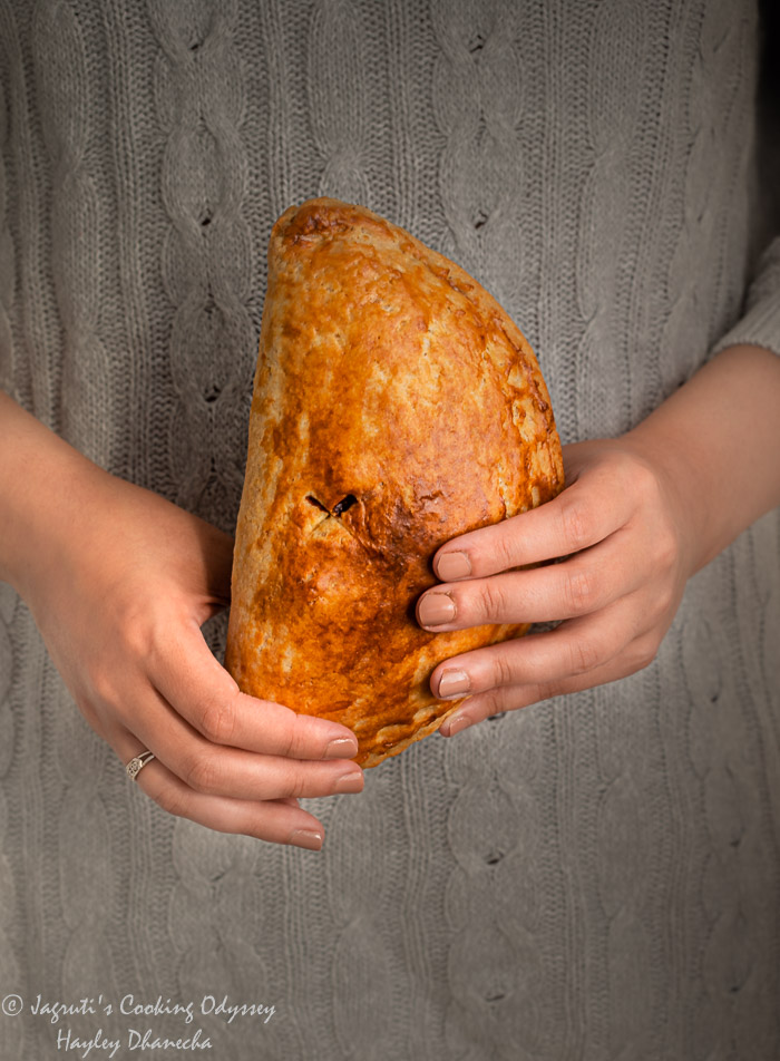 A girl is holding vegan flaky cornish pasty in her hands