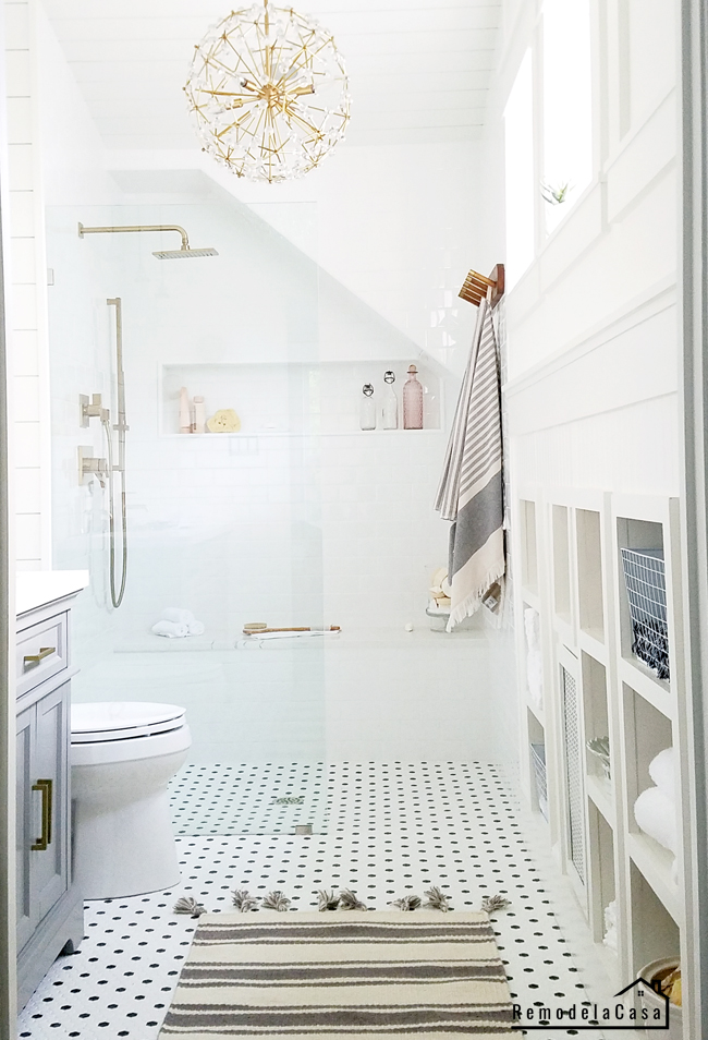 a white small bathroom with shiplap, floral pendant light, grey and gold tones