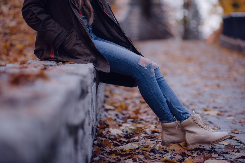 Woman Wearing Black Jacket Blue Distressed Jeans And Brown Boots