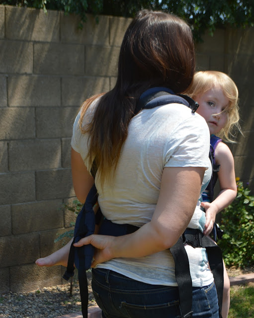 Momma is seen from the back reaching behind her with one hand to grab the shoulder strap