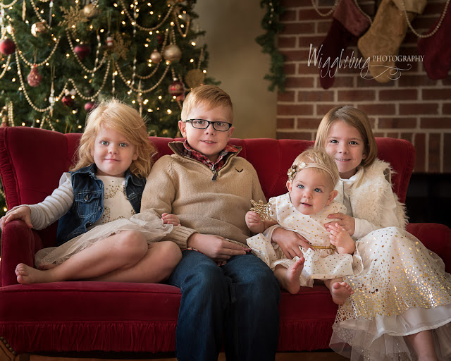 Traditional Christmas tree photo with four children dressed up in holiday clothing