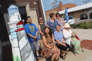 7 participating artists from the Storm Lake Lighthouse Project, next to the lighthouse painted by Haley McAndrews.