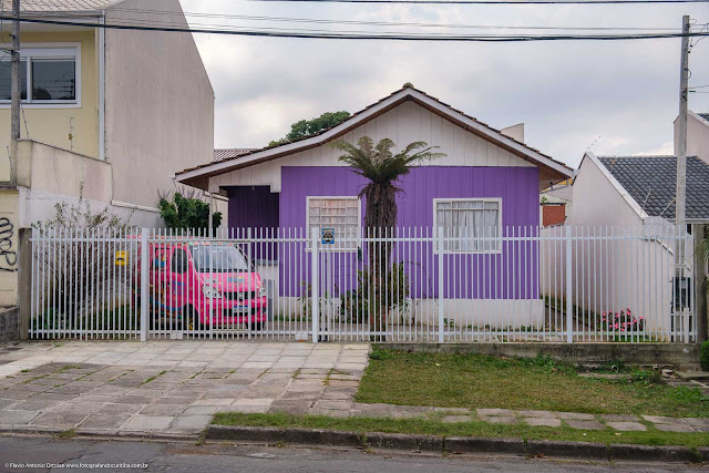 Carro rosa em frente a casa roxa e branca