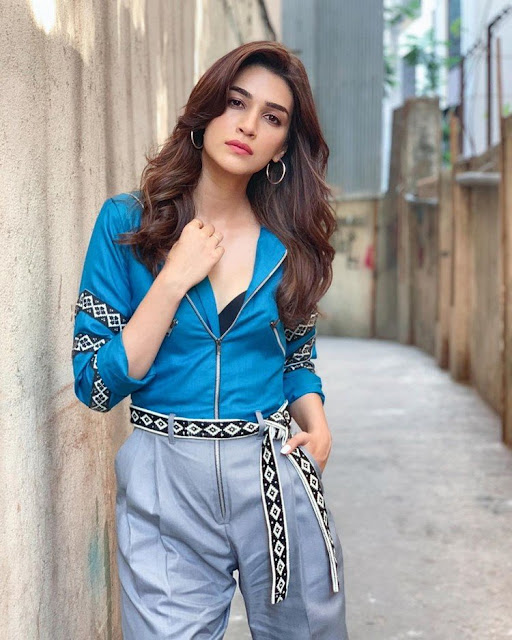 Bollywood actress Kriti Sanon in a blue shirt and grey pants, exuding confidence and style.
