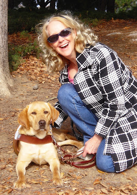 Picture of Wendy and Glenda at a park with the fall leaves all around.  Wendy is in a down and is in harness.  Glenda is one knee and she has a huge smile on her face.