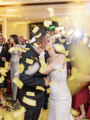 bride and groom kissing through confetti