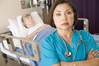 Photo of an unhappy nurse standing near a patient's bedside