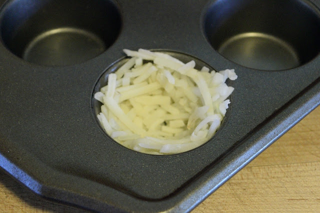 The thawed hash brown potatoes formed into the muffin pan as a nest.