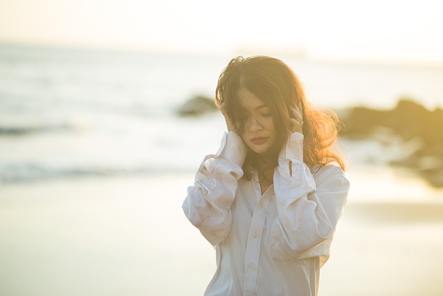 An image of a very beautiful girl standing on the beach and holding her neck with the hands in a very sexy manner- sad girl dp