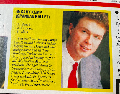 A screen shot of an answer by Gary Kemp from Spandau Ballet about what he puts in his shopping basket. '1. Bread. 2. Cheese. 3 Milk. I'm terrible at buying things. I walk in and I always end up buying bread, cheese, and milk, and go home and sit there thinking 'what can I make?' I'm no good at buying stuff at all. My brother Martin is brilliant. He's got a Marks and Spencer's sweet shop inside his fridge. Everything! His fridge is like a Marks and Spencer's food counter. But I'm terrible. I only eat bread and cheese.