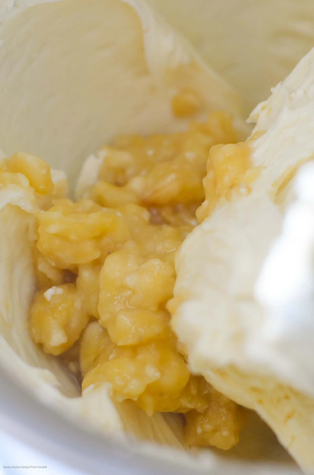 Banana added to beaten Cream Cheese and Sugar in a stainless steel mixing bowl.