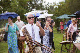 Guests quickly springing into action and moving chairs under the cover of the reception tent.