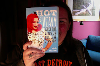 Charlotte at her desk holding her copy of the book to the camera