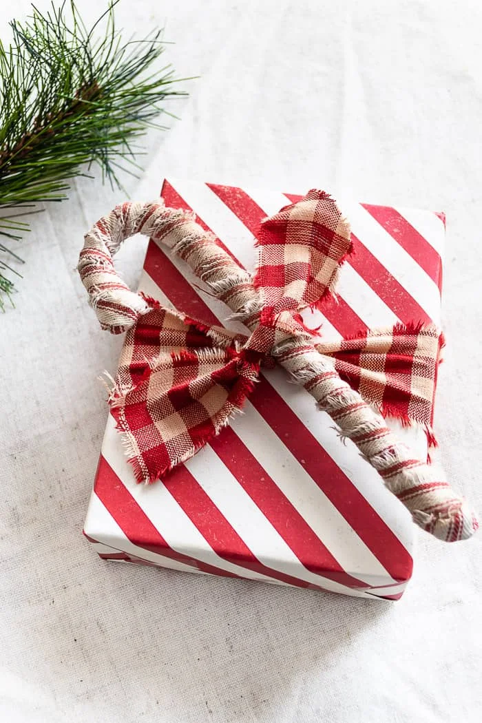 red ticking stripe primitive candy cane tied to package with red check homespun fabric strip