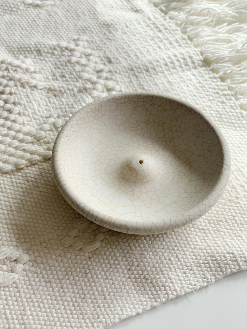 white ceramic incense holder over white throw