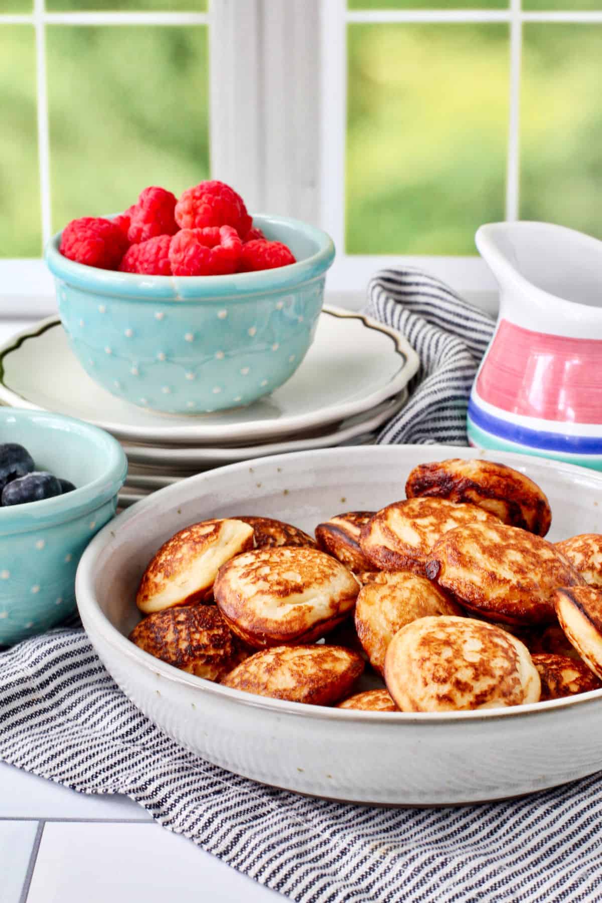 Mofo Gasy - Madagascar Yeasted Pancakes with blueberries and raspberries on the side in bowls.