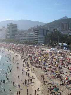 Crowded Ipanema Beach with the Christ the Redeemer statue in the distance.