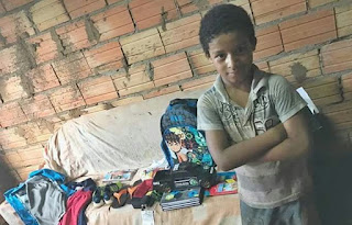 O menino Gabriel feliz com o material escolar que recebeu em doação