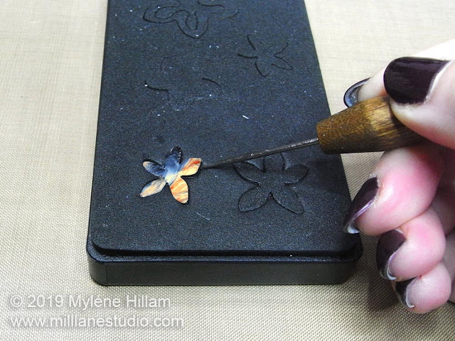 Using a needle tool to remove a stuck die cut from the die.