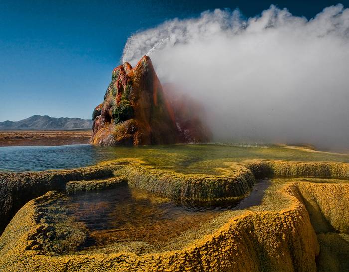 Fly Geyser is a little-known tourist attraction, even to Nevada residents. It is located near the edge of Fly Reservoir and is only about 5 feet (1.5 m) high, (12 feet (3.7 m) counting the mound on which it sits). The Geyser is not an entirely natural phenomenon, and was accidentally created in 1916 during well drilling. The well functioned normally for several decades, but in the 1960s geothermally heated water found a weak spot in the wall and began escaping to the surface. Dissolved minerals started rising and accumulating, creating the mount on which the geyser sits, which continues growing. Today water is constantly spewing, reaching 5 feet (1.5 m) in the air. The geyser contains several terraces discharging water into 30 to 40 pools over an area of 30 hectares (74 acres). The geyser is made up of a series of different minerals, which gives it its magnificent coloration.