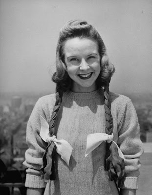 Pigtails on a felt bonnet on a comely young lass