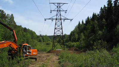 Kraftledning i skog med grävmaskin intill