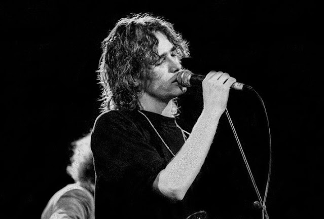 A man in black shirt sings at a microphone