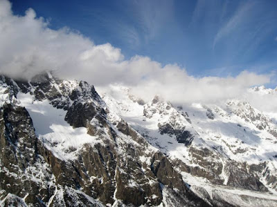 Blue skies and fluffy cloud over snowy peaks