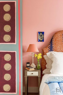 Beata Heuman bedroom with salmon pink walls, hand painted door, and patterned upholstered headboard