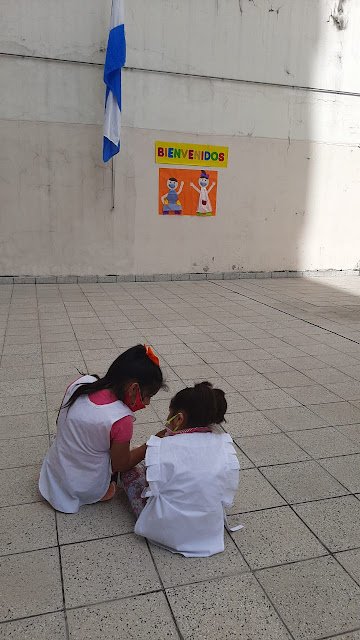 Danna y Luz sentadas interactuando en el patio de la escuela