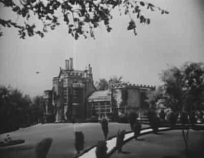 A large country house with prominent towers stands in the hills