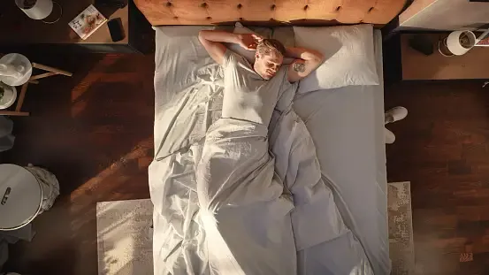 A man sleeping on the bed with his back
