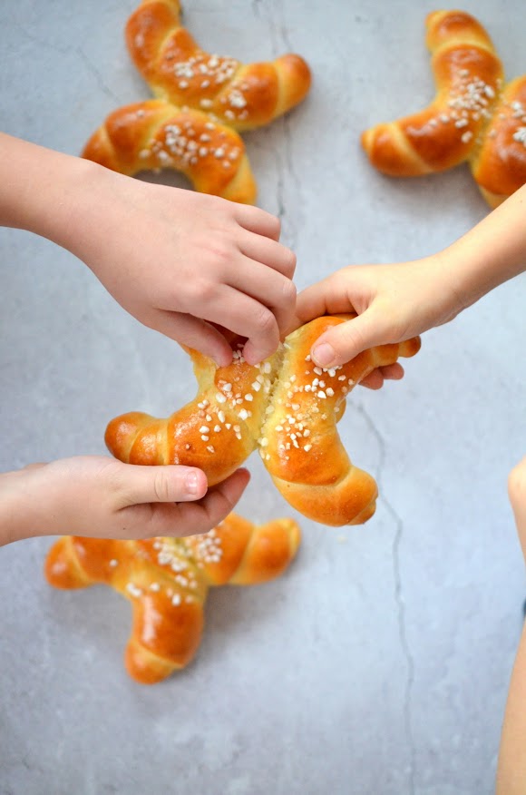 Zwei Kinder halten ein Martinskipferl zum Teilen in den Händen. Gemeinsam teilen sie es.