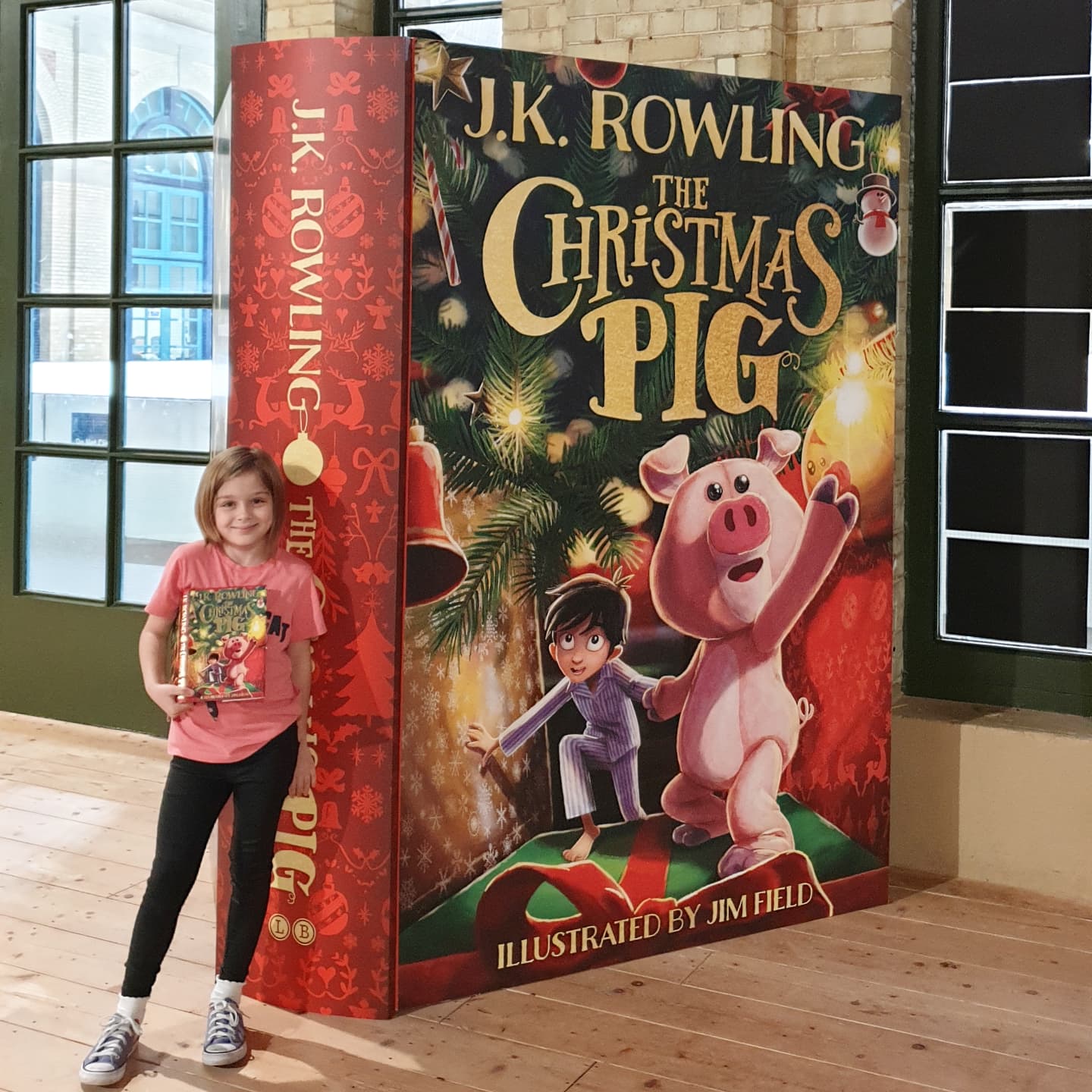 girl standing in front of a giant christmas pig book