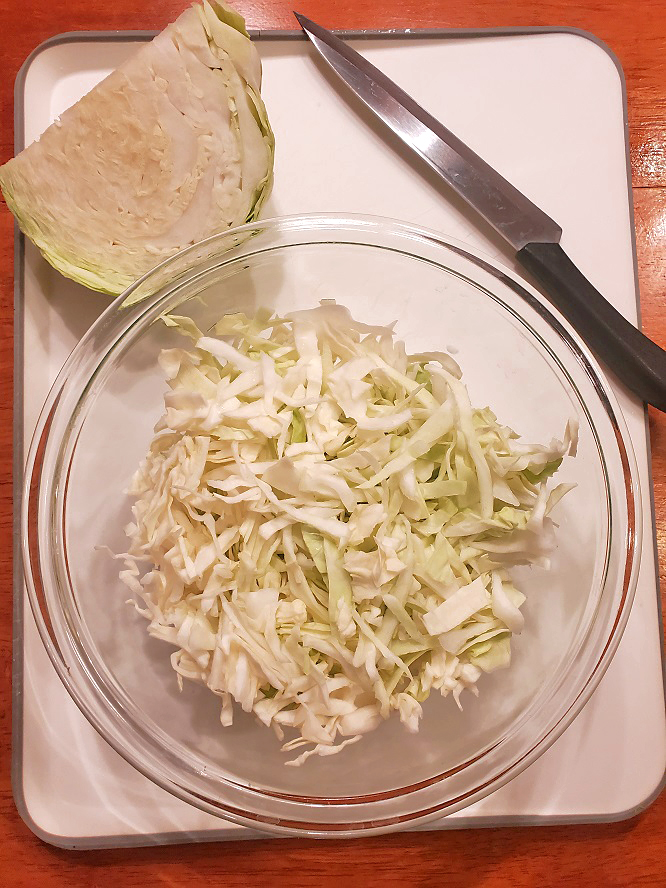 this is sliced shredded cabbage using a cutting board and sharp knife in a glass bowl