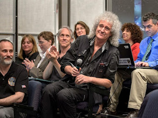 Astrophysicist Dr. Brian May is recognized during a July 17, 2015 New Horizons science briefing at NASA Headquarters, Washington, D.C. May spent a long birthday weekend with the science team, attending two morning science plenaries, a meeting with the Student Dust Counter group, and working on stereo images of Pluto with the Geology, Geophysics and Imaging (GGI) team.