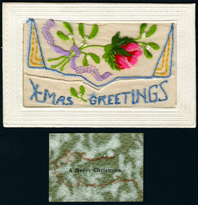 An embroidered card featuring a large red and pink rose with green leaves tied with a lavender ribbon. A blue and yellow decorative border surrounds the bottom-half of the flower. 'X-Mas Greetings' is embroidered below in baby-blue thread. A card with green, white and red decorations reads 'Merry Christmas' and is separate from the embroidered card.