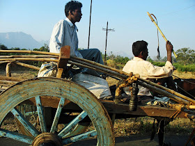 two men riding bullock cart on country road