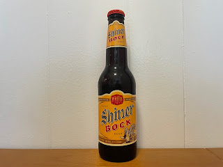 An unopened bottle of Shiner Bock sitting on a kitchen table.