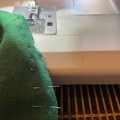 A piece of green tweed going through a sewing machine