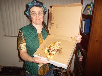 Cynthia Parkhill holds open pizza box tilted toward viewer. Inside, occupying less than half of surface space, are three small slices of pizza