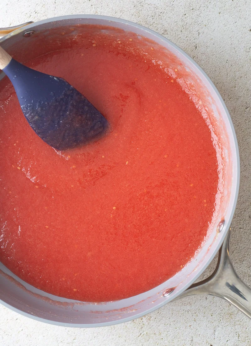 Guava jam with additional coloring in a yellow non-stick pot.