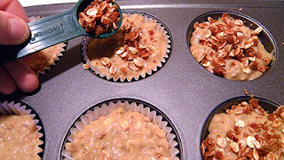 Hand sprinkling topping onto muffins from spoon