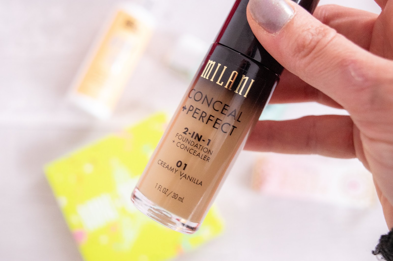A close up of the Milani 2 in 1 Foundation and Concealer. The bottle is glass with a black top and contains a fair skin toned liquid.