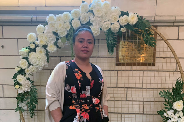 Photograph of Amelia standing in front of white floral arrangement.